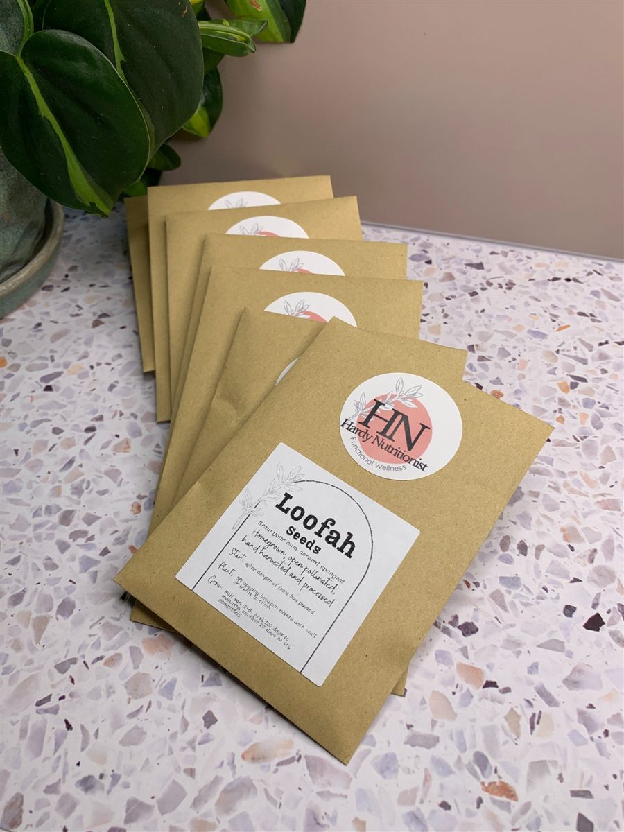 Kraft-paper seed packets labeled Loofah Seeds, fanned out on a marble surface.