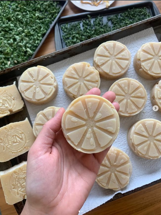 Handmade soap bars cooling and drying on a wire rack tray.