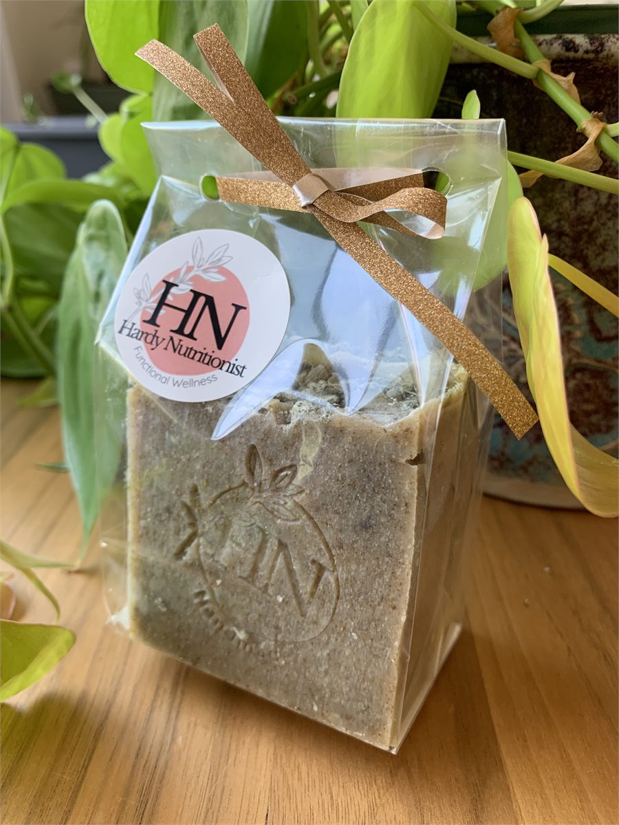 An herb-flecked soap bar stamped with the Hardy Nutritionist logo, in a clear gift bag tied with a gold ribbon.
