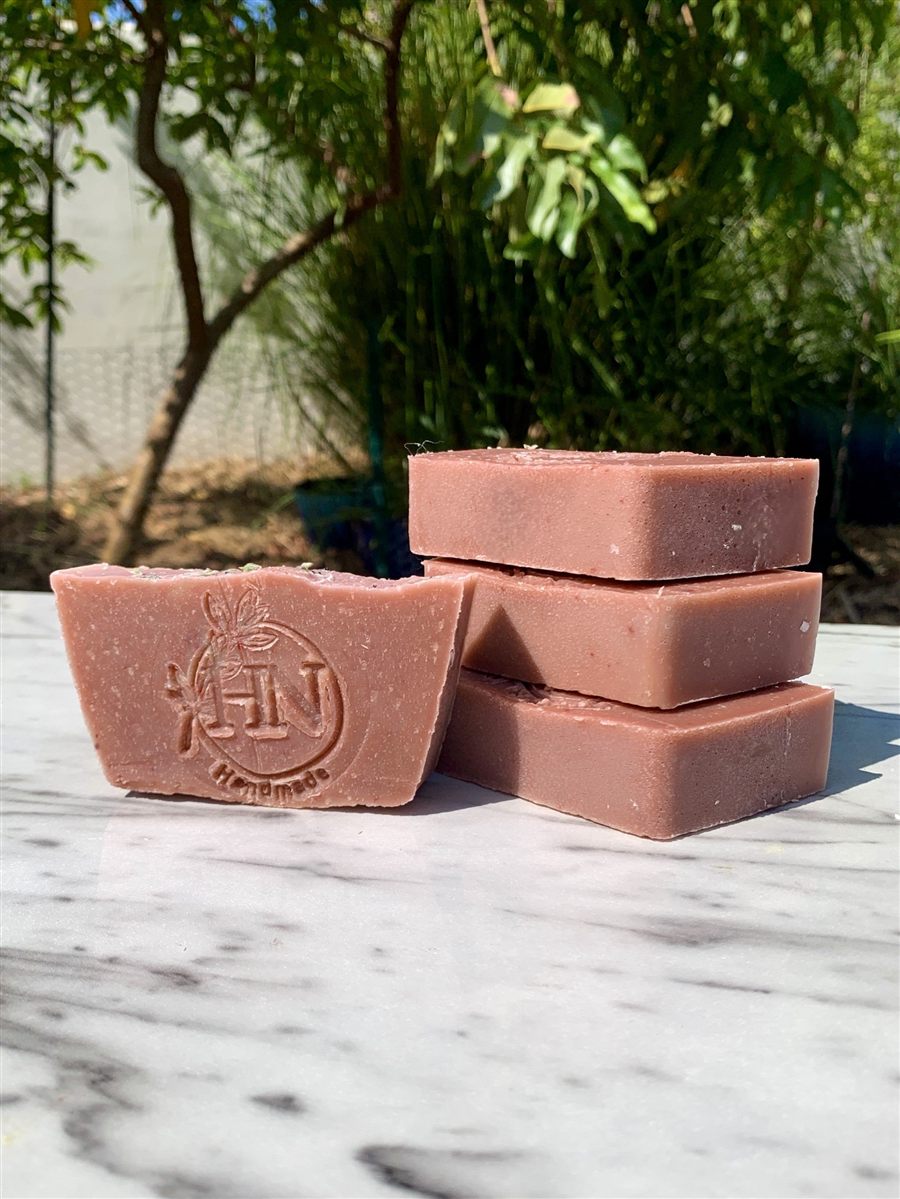 A citrus-pink soap bar stamped with the Hardy Nutritionist logo, stacked on a marble surface.